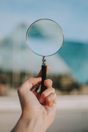 A vertical selective shot of a person holding a clear magnifying glass