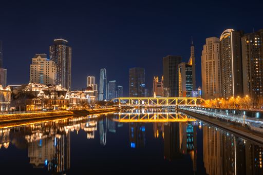 City scape with modern buildings and towers with a river in a city by night