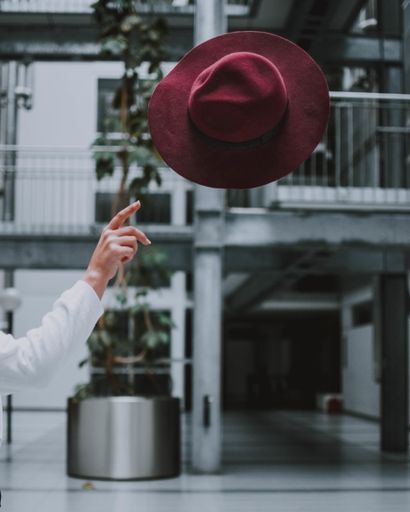 A vertical selective shot of a person throwing a red hat into the air