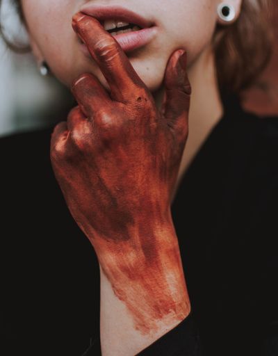 A vertical selective shot of a female touching her lips with a red painted hand