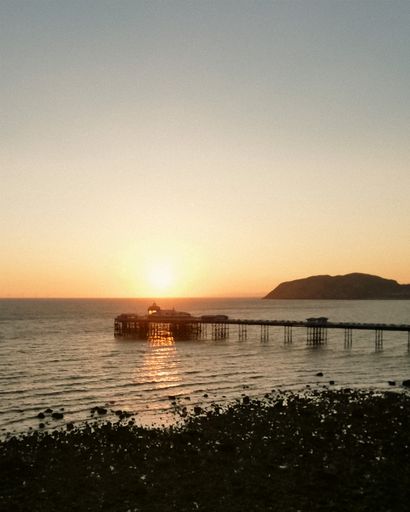 A vertical shot of a silhouette of a pier in the sea against the background of a beautiful sunset
