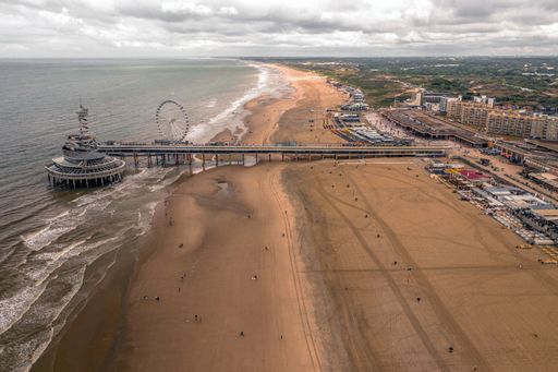 A sandy beach with a Ferris wheel and pier