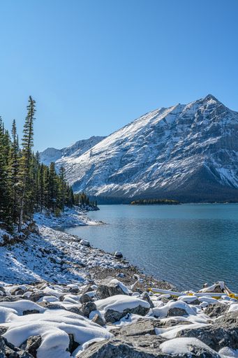A vertical shot of a beautiful winter landscape with the lake and mountains. Canadian nature.