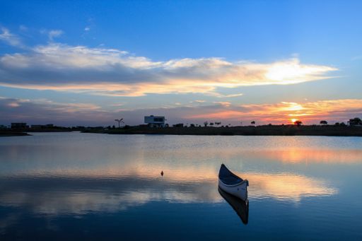 The boat on the river gleaming under the sunset piercing through the clouds