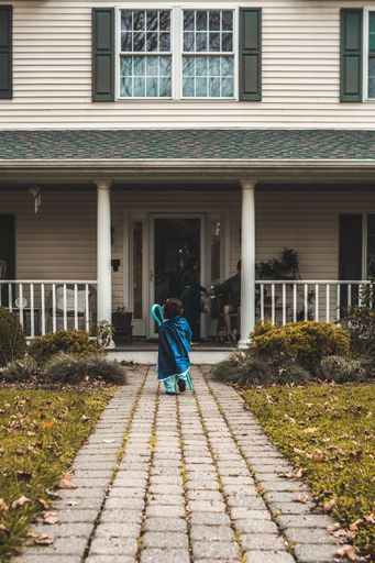 A vertical shot of a child with a costume near the white building