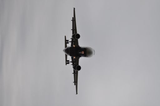 A vertical low angle grayscale shot of a plane flying in the sky