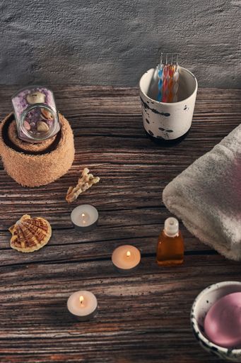 A high angle shot of a set of towels, diffuser, and candles on a wooden surface