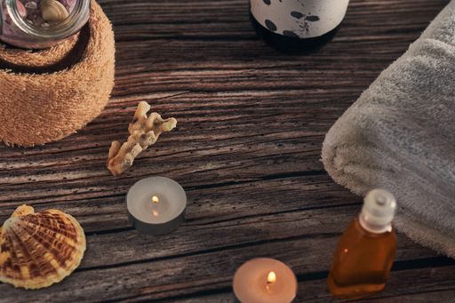 A lot of spa elements on a wooden surface, set of towels, diffuser, and candles