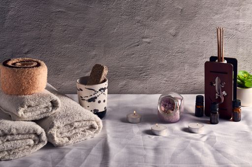 A lot of spa elements on a wooden surface, set of towels, diffuser, and candles