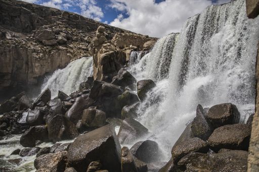 A mesmerizing shot of a wild waterfall under the cloudy vibrant sky
