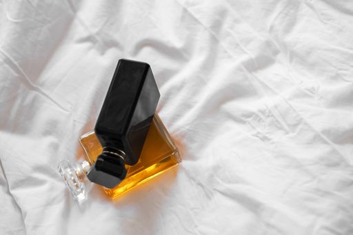 A top view of two perfume bottles on a white bedsheet