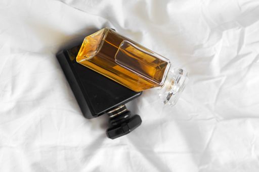 A top view of two perfume bottles on a white bedsheet