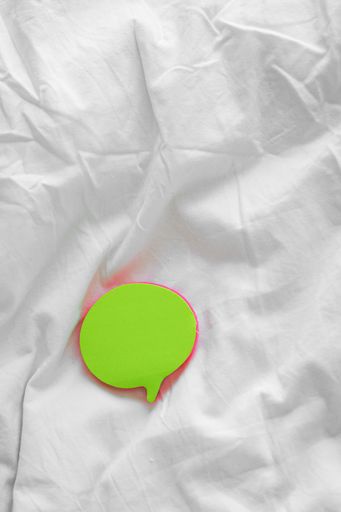 A vertical shot of colorful bubble-shaped sticky papers on a white bedsheet