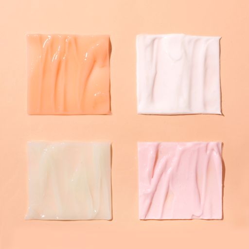 A top view of four pastel-colored square skincare texture swatches on a pink background