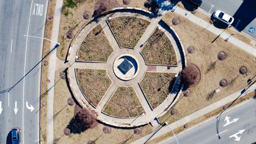 A top view of a circular park surrounded by roads and cars
