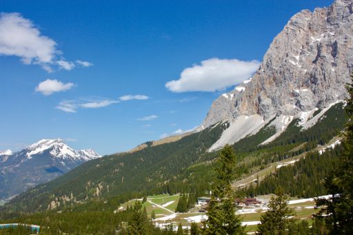A wide shot of beautiful rocky mountains with a lot of green trees under the cloudy sky