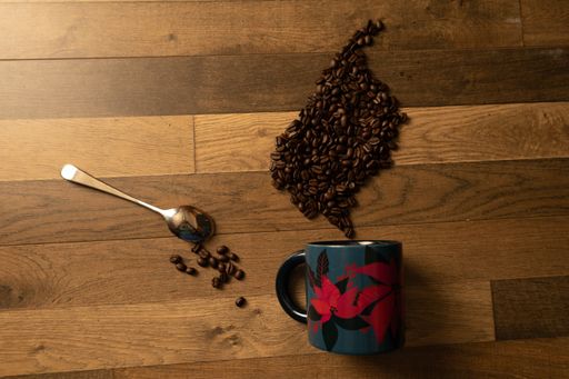A top view of coffee beans in a decorative style with a blue mug and a spoon on parquet floor