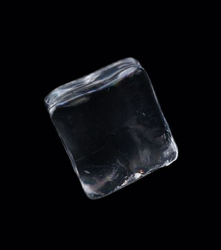 A closeup shot of a floating ice cube on a black background