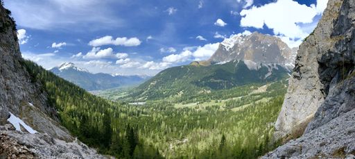 A beautiful scenery of high rocky mountains and a green land under the cloudy sky