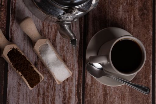 zenithal view of a coffee cup with milk jug and wooden spoons on a wooden table with text space