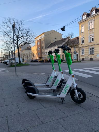 A vertical shot of electro scooters parked on the roadside in Linz on a sunny spring day
