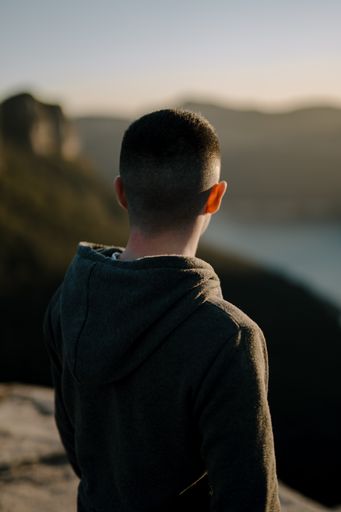 A vertical shot from behind of a man looking at nature in a sunny day.