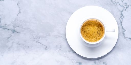 A top view shot of strong espresso in a white cup on a marble surface