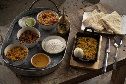 A view of different types of dishes and sauces served with lavash and lime on a wooden table