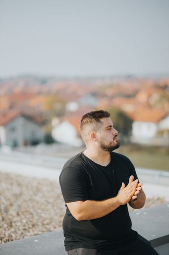 A vertical closeup shot of a young Caucasian male sitting and looking away on a blurry background