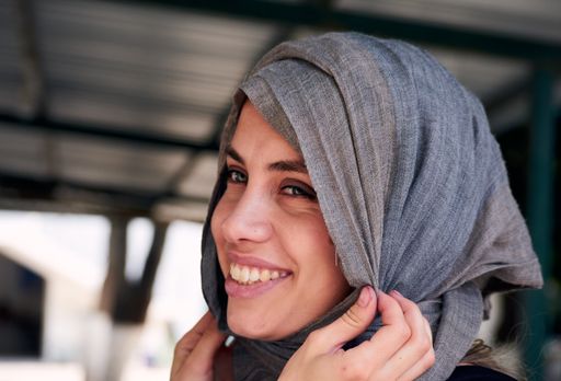A young smiling Muslim girl fixing her hijab