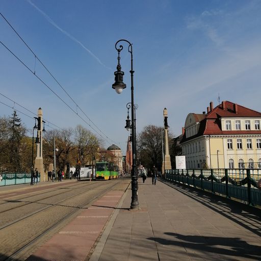 A scenic view of a lantern on the Most Teatralny bridge with a green tram in the city center