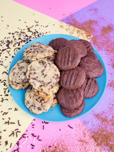 A top view of two kinds of sweet cookies with chocolate and white cream on a blue plate