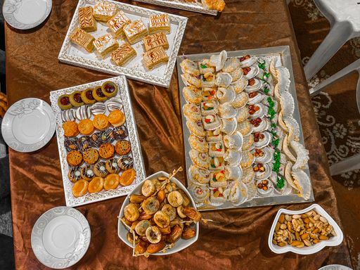 A top view of various colored eastern delicious sweets and dry fruits on a table with a brown tablecloth