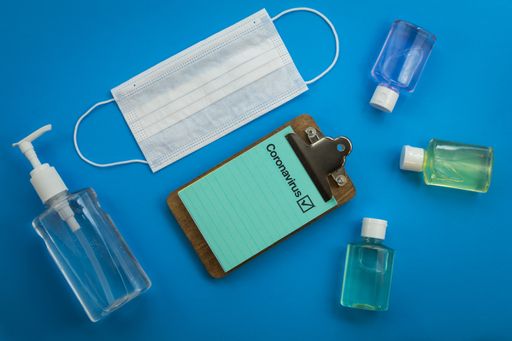 A prescription note next to sanitizers and a medical mask on  a blue background