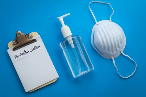 A closeup of a hand sanitizer, a mask and a prescription note on a blue surface
