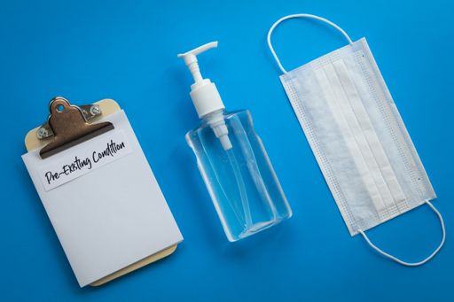 A closeup of a hand sanitizer, a mask and a prescription note on a blue surface