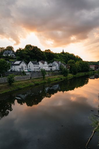 A vertical shot of a calm river with a small town on the side at sunset