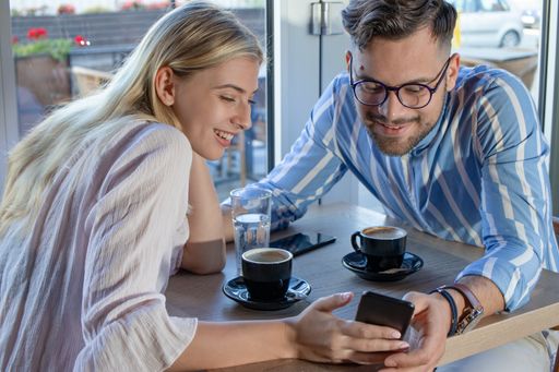 A beautiful young happy couple taking a selfie on the smartphone while sitting in a cafe