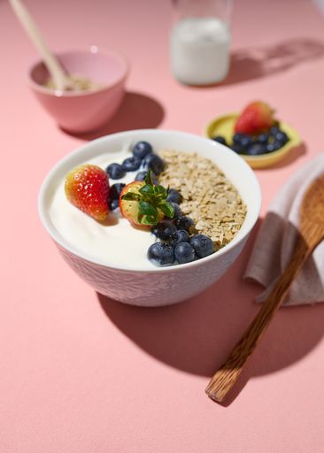 The yogurt with berries, strawberries and muesli in the pink background