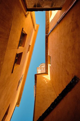 A vertical low angle shot of clear sky in between of two rural buildings in France
