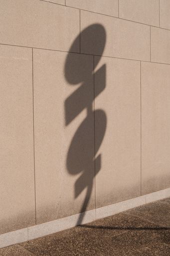 A beautiful shot of the shadow of street traffic sign on the stone urban wall outdoors on a sunny day