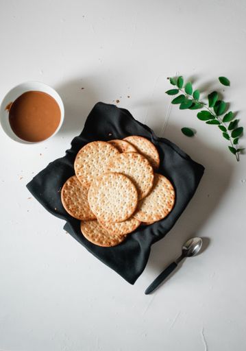 A high angle shot of snacks and a bowl of caramel on a white surface