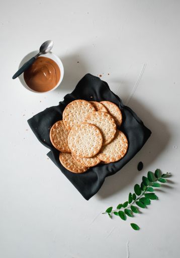 A high angle shot of snacks and a bowl of caramel on a white surface