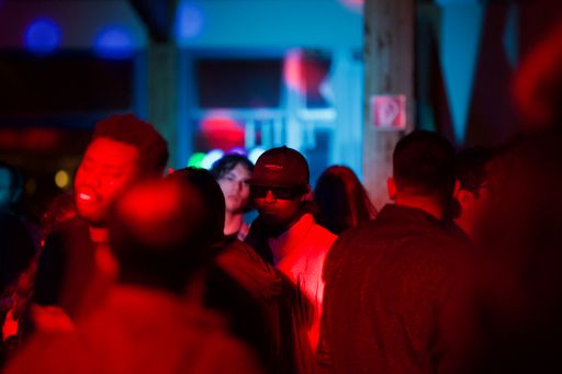 A person looking at a camera from the crowd under the red light