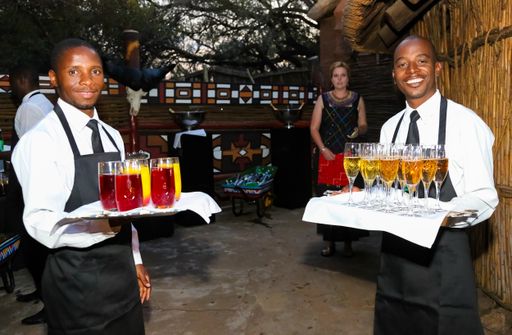 The African waiters holding tray of welcome drinks and smiling at party event in Johannesburg, South Africa