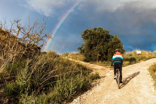 A low angle shot of a rainbow and a male biker in the countryside in Spain