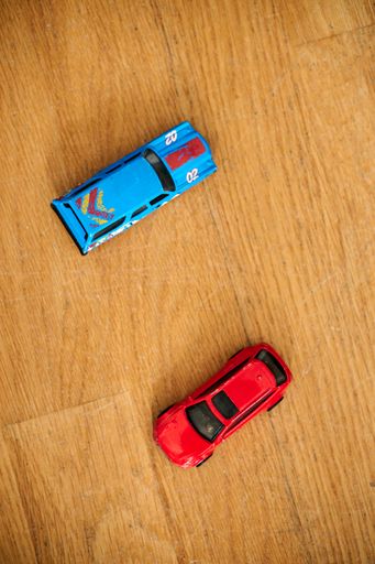 The blue and red Mattel Hot Wheels toy model cars on a wooden floor
