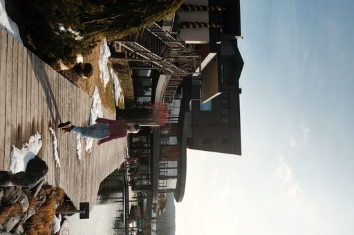 A vertical shot of a lady walking on a pier next to buildings in Tyrol, Italy