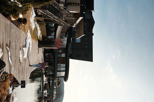A vertical shot of a lady walking on a pier next to buildings in Tyrol, Italy