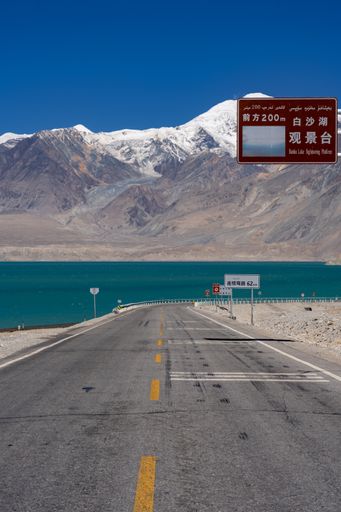 A vertical shot of an asphalt road with mountains in the background